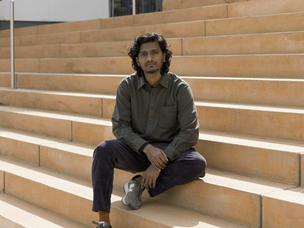 Indian artist Amol K Patil seated on steps. Photo by Bea Borgers.