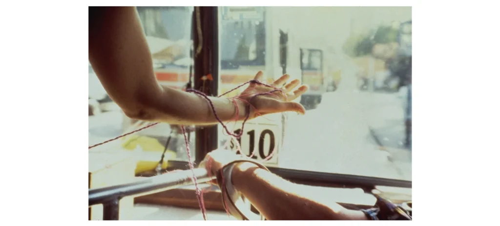Guante / The Glove performance by Cecilia Vicuña, with red thread wrapped around outstretched hands